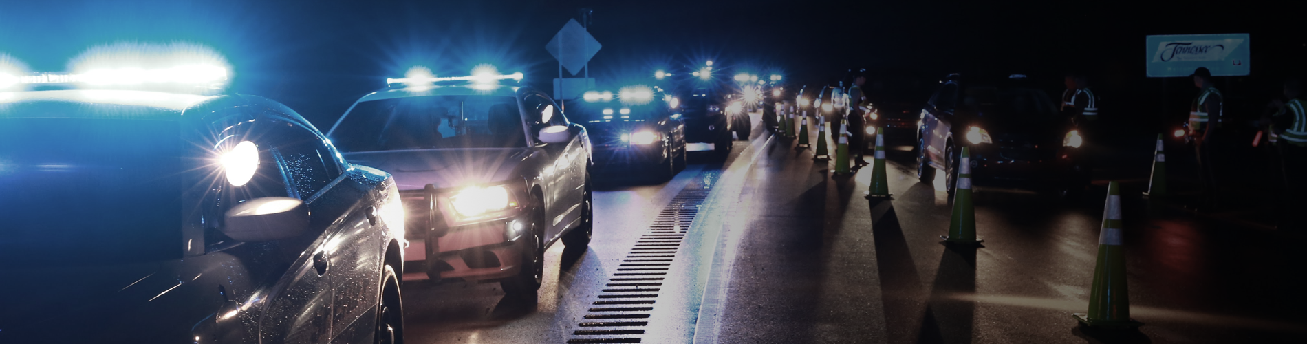 Background Image: A DUI checkpoint at night, several police vehicles with bright lights in the roadway.